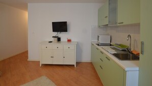 A small, modern kitchen with white cabinets, a microwave, a sink, and a flat-screen TV mounted on the wall. - Blissful Bay Apartment Rovinj Center (Rovinj)