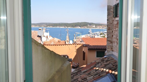 A view from a window overlooking a harbor with boats, buildings, and a clear sky. - Blissful Bay Apartment Rovinj Center (Rovinj)