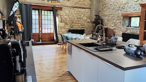 Une cuisine chaleureuse avec un mur en pierre, un plancher en bois et un îlot central doté de sièges.
