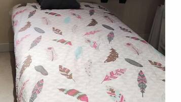 Een slaapkamer met een bed, een donker hoofdeinde en een schuin dak.