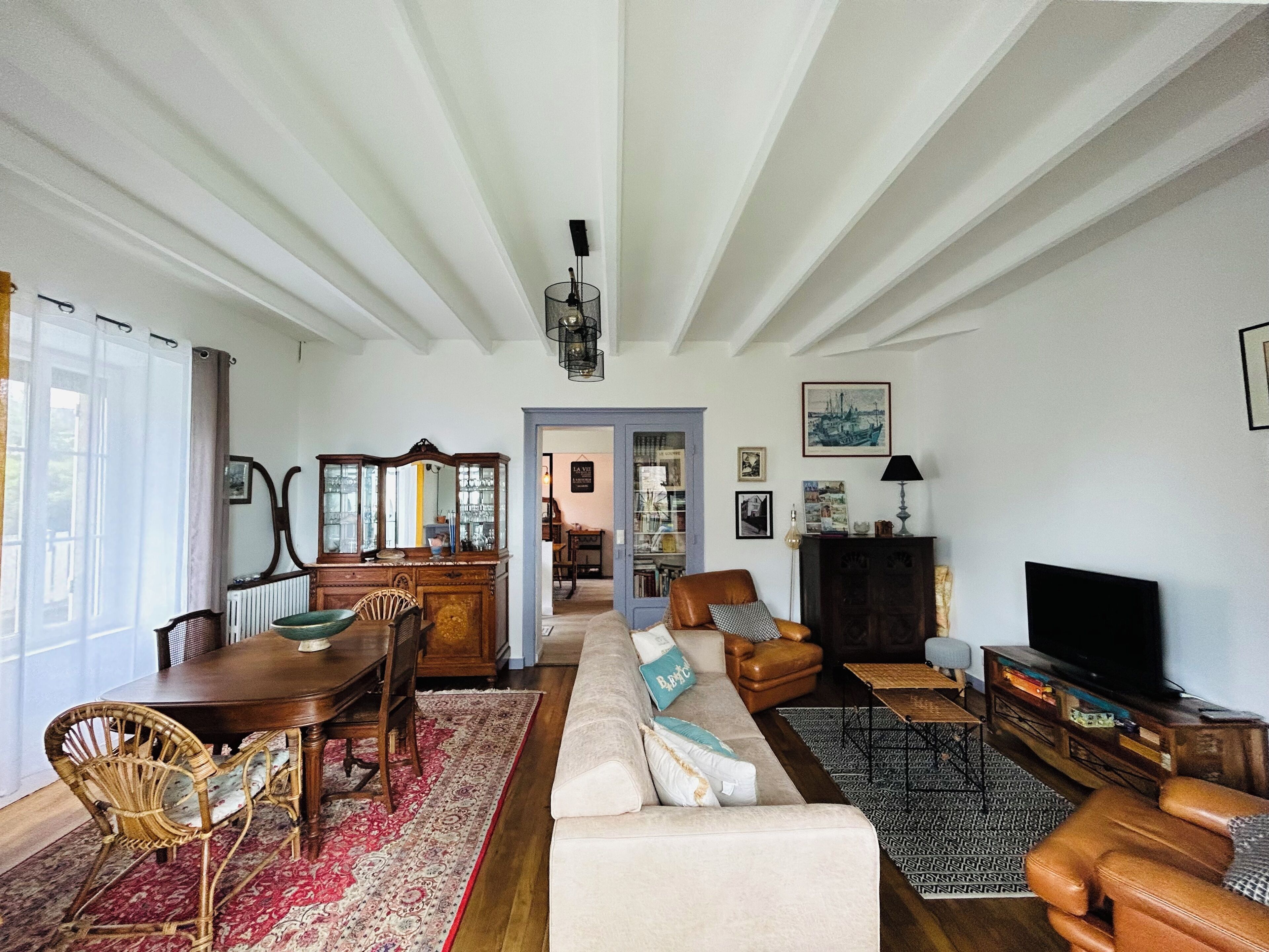 Ein geräumiges Wohnzimmer mit einem Holzesstzimmer, einem Sofa, einem Fernseher und einem Bücherregal.