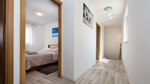 Una habitación de hotel con una cama, suelo de madera y un pasillo que conduce a otra habitación.