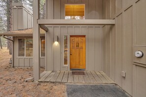 A two-story building with a wooden front door, a small porch, and a window above the door.