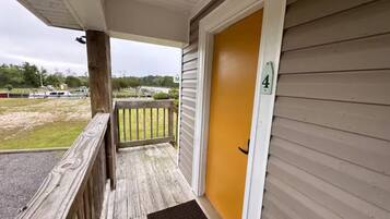A wooden porch with a yellow door marked with the number 4.