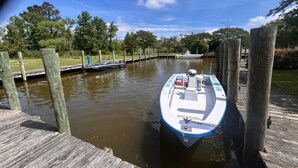 A boat docked at a wooden pier with a calm water body and trees in the background. - Knot Four- Balcony View of ICW- Dog Friendly! (Coinjock)