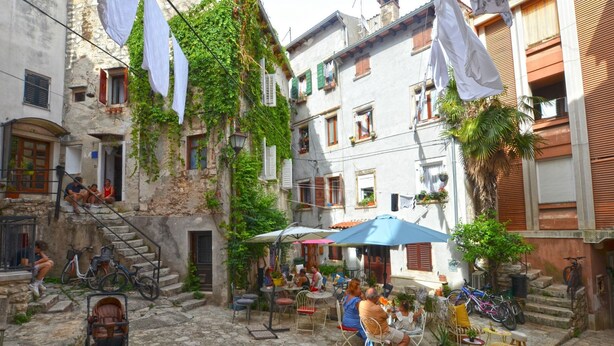 A cobblestone courtyard with outdoor seating, bicycles, and laundry hanging on lines. - Radiant and Trendy Downtown Rovinj Apartment (Rovinj)