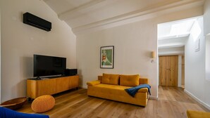 A modern living room with a flat-screen TV, wooden cabinet, yellow sofa, and a wooden floor. - Radiant and Trendy Downtown Rovinj Apartment (Rovinj)