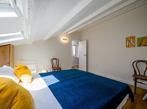 A bedroom with a bed, a chair, a wooden wardrobe, a window, and a door. - Radiant and Trendy Downtown Rovinj Apartment (Rovinj)