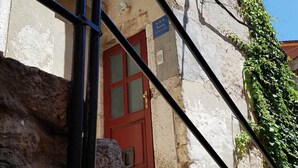 A narrow street with a red door, a stone wall, and a sign indicating an apartment. - Radiant and Trendy Downtown Rovinj Apartment (Rovinj)