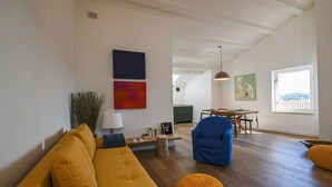 A spacious living room with a yellow sofa, a blue armchair, and a dining area with a table and chairs. - Radiant and Trendy Downtown Rovinj Apartment (Rovinj)