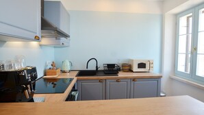 A compact kitchen with a wooden countertop, a black sink, a white microwave, and a kettle. - Sunny Rovinj Apartment With Sea View (Rovinj)
