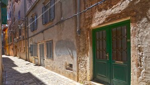 A narrow cobblestone street lined with historic buildings, featuring a green door with a decorative grille and shuttered windows. - Sunny Rovinj Apartment With Sea View (Rovinj)