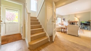 A staircase leading to a living area with a sofa, a television, and a fireplace. - Corner Cottage, Brancaster, Norfolk (Brancaster)