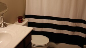 A bathroom with a white sink, a mirror, a toilet, and a striped shower curtain. - Cozy 2-bedroom condo in Waterloo south side with AC, WiFi & cable TV (Waterloo)