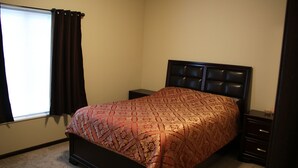 A bedroom with a bed, a nightstand, a dresser, and a window with curtains. - Cozy 2-bedroom condo in Waterloo south side with AC, WiFi & cable TV (Waterloo)