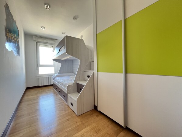 Un dormitorio moderno con literas, almacenamiento integrado y un ventanal amplio.
