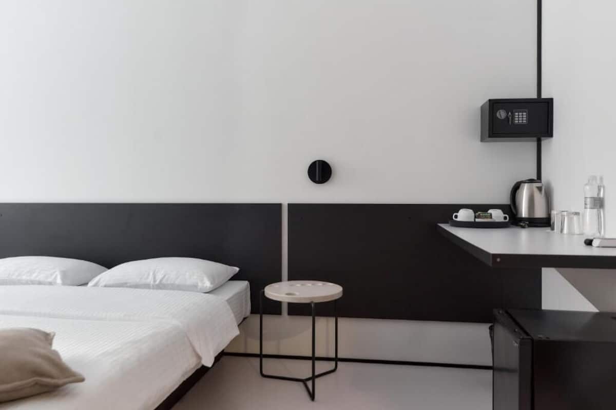 Een moderne hotelkamer met een bed, een klein rond tafeltje, een waterkoker en een koffiezetapparaat op een aanrecht.