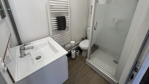 Un bagno moderno con lavandino bianco, water e doccia vetrata.