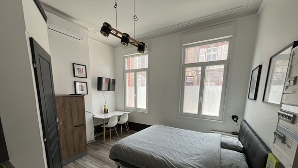 Una camera da letto con un letto, una scrivania, una sedia, una TV e una finestra.