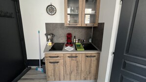 Una cucina compatta con mobili in legno, un lavello incassato e un orologio appeso al muro.