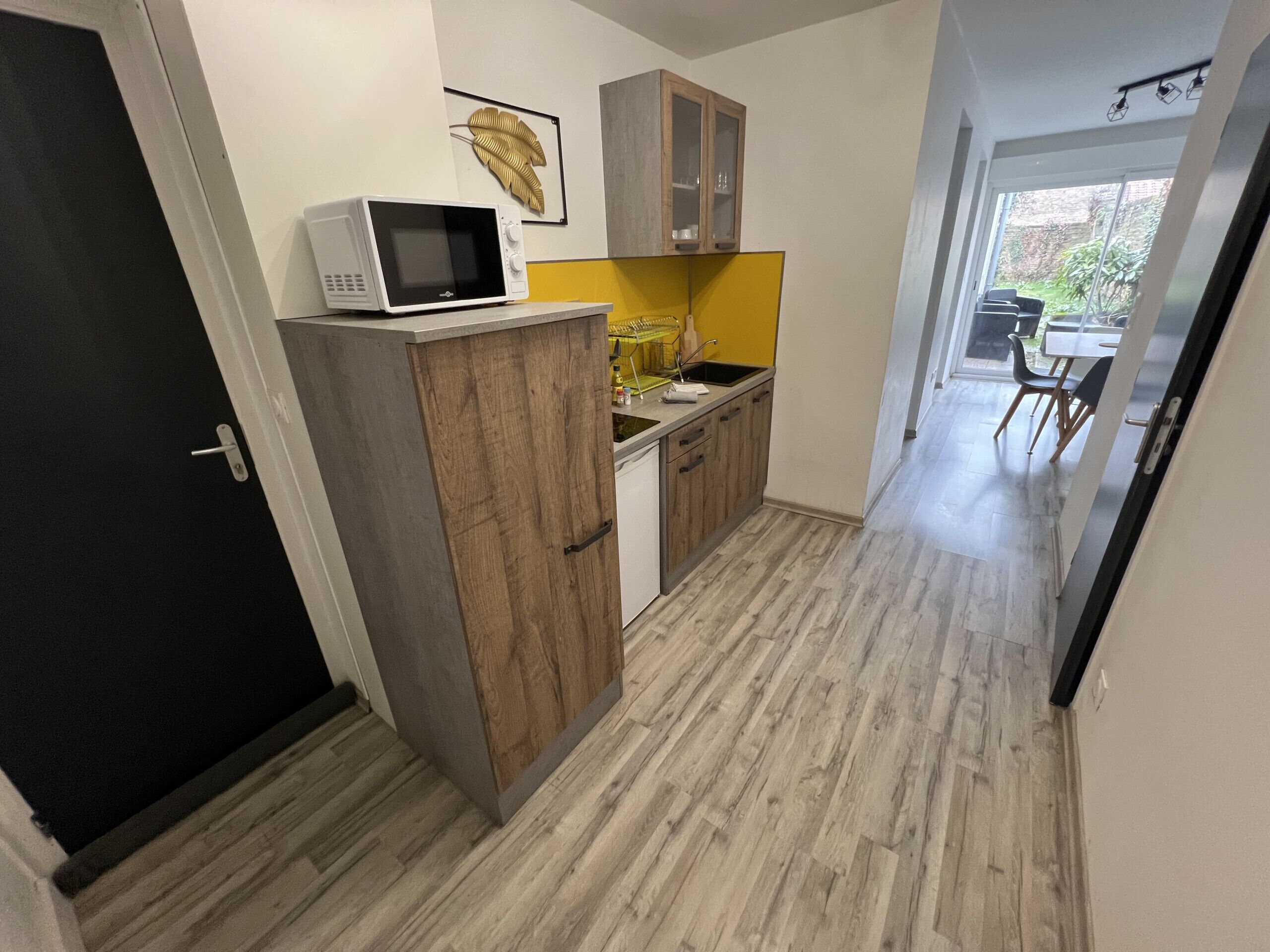 Una cucina compatta con forno a microonde sul ripiano, mobili in legno, un lavello e una finestra vista giardino.