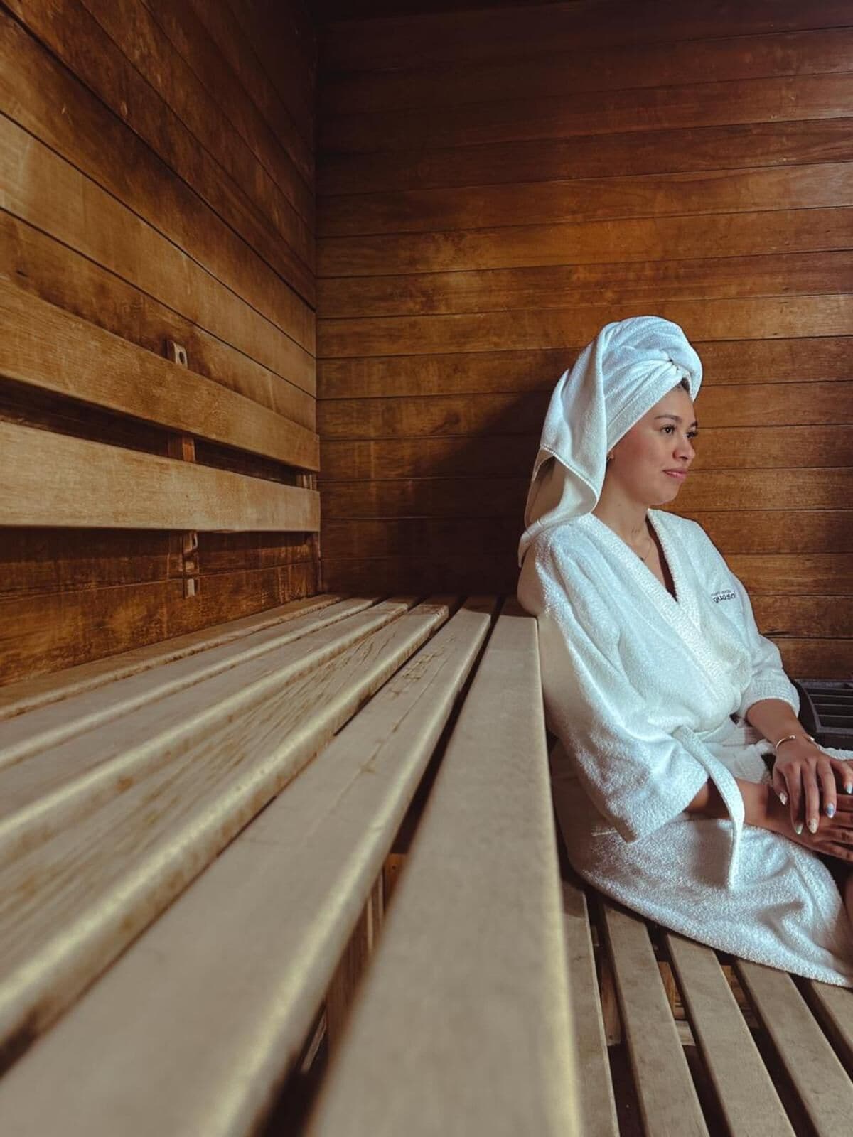 Una persona sentada en un banco de madera en una habitación con paredes de madera.