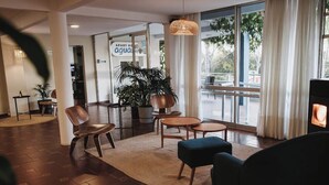 A modern lobby with a seating area, large windows, and a visible sign for 'APART HOTEL'.