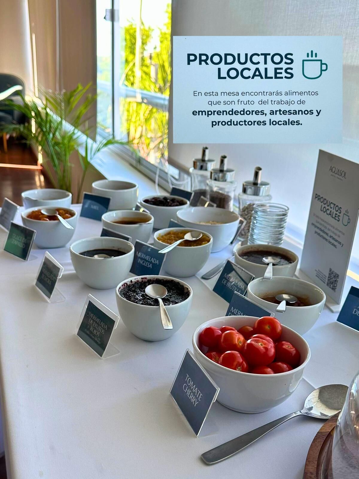 A buffet table with various food items labeled, including a bowl of cherry tomatoes.