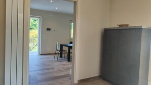 A room with a wooden floor, a dark cabinet, and a dining area visible through an open door. - Holiday home for 5 Lido di Camaiore (Lido di Camaiore)