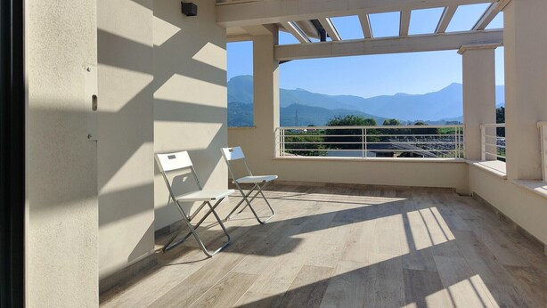 A balcony with a view of mountains, two white chairs, and a tiled floor. - Holiday home for 5 Lido di Camaiore (Lido di Camaiore)