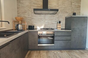 A modern kitchen with a built-in oven, a gas stove, and a stainless steel sink.