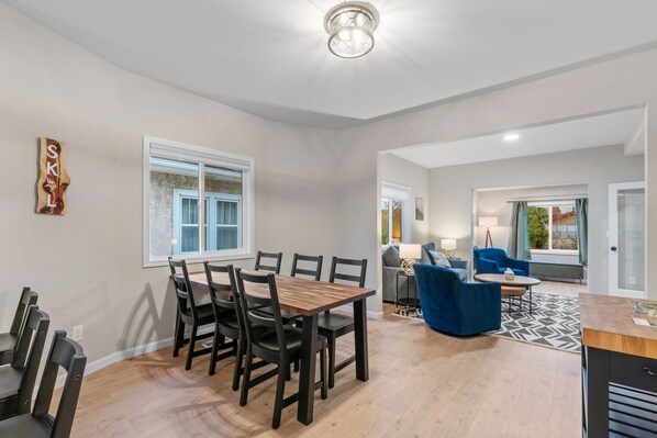 A spacious living area with a dining table, chairs, a sofa, a coffee table, and a patterned rug. - MINNeSTAY* Red Maple | Karaoke! (Minneapolis)