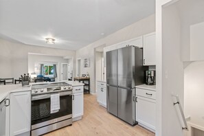 A modern kitchen with white cabinetry, stainless steel appliances, and a wooden floor. - MINNeSTAY* Red Maple | Karaoke! (Minneapolis)