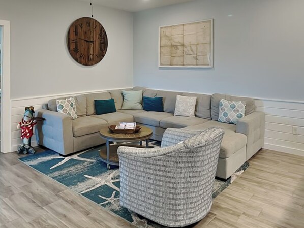 A modern living room with a sectional sofa, a round coffee table, and a patterned rug.