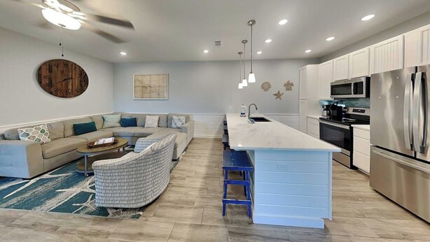 A modern kitchen with a central island, built-in appliances, and a seating area with a sofa and coffee table. - Port A Retreat w/ Rooftop Balcony + Community Pool! (Port Aransas)