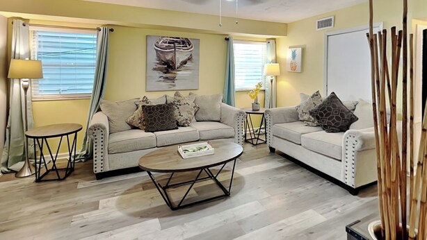 A living room with two sofas, a coffee table, and a painting of a boat on the wall.