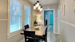 A dining area with a wooden table, black chairs, and a hanging light fixture.