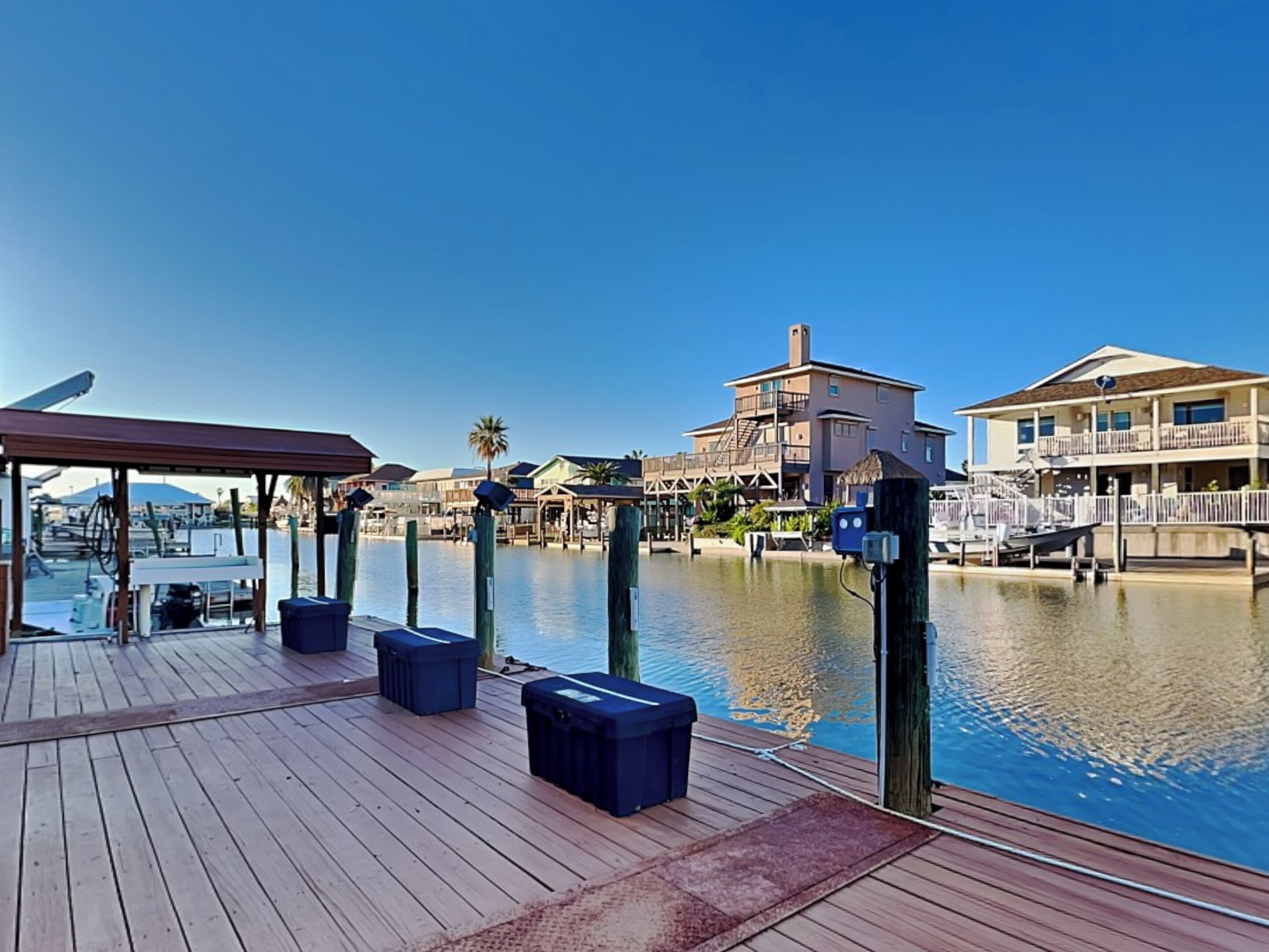 A wooden deck with seating, a marina, and buildings in the background.