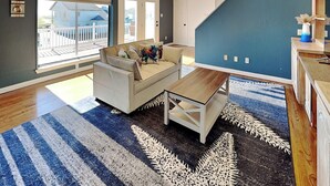 A modern living room with a sofa, coffee table, and a large window. - Pirate's Paradise | Waterfront & Private Pool (Rockport)