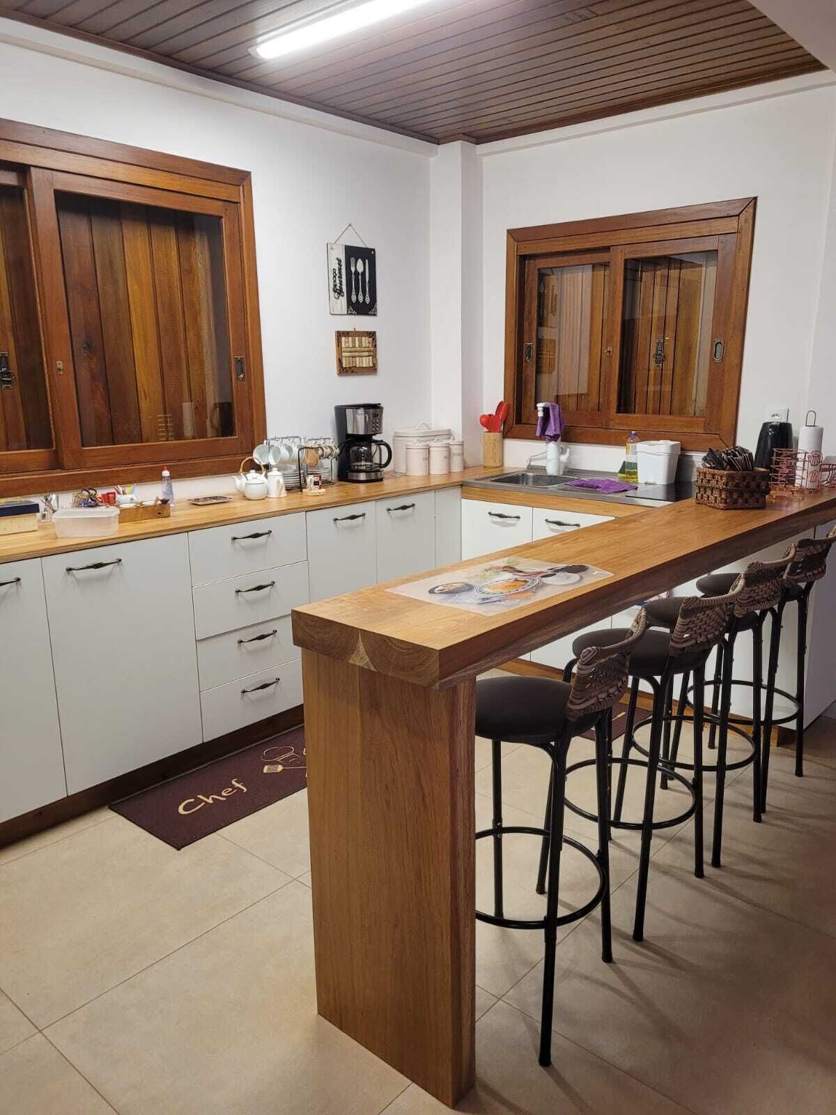 A kitchen with wooden cabinets, a central island with bar stools, and a tiled floor.
