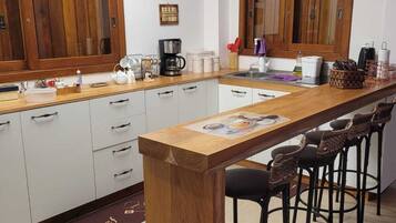 A kitchen with wooden cabinets, a central island with bar stools, and a tiled floor.