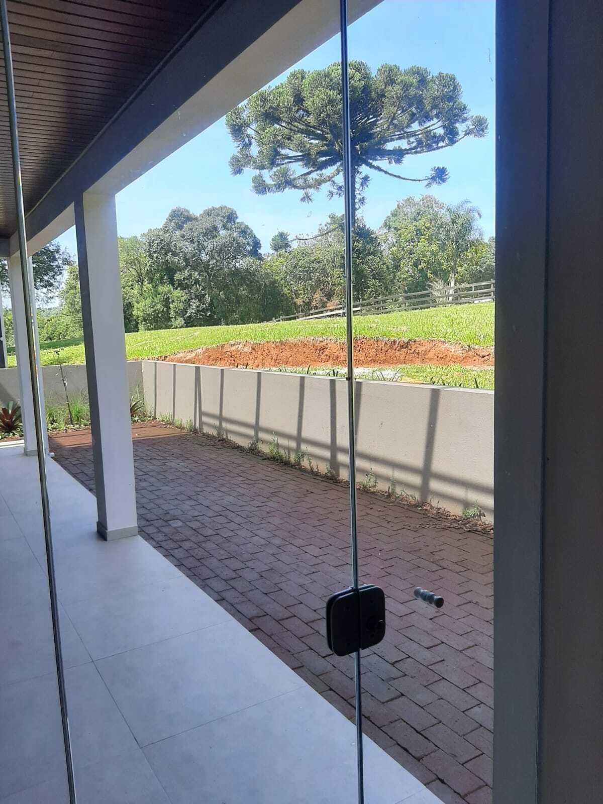 A covered outdoor area with a view of a field and trees.