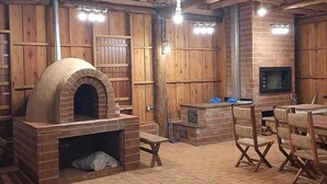 A rustic wooden interior with a brick oven, wooden tables, and chairs. - Invernada Blessmann  (Vespasiano Corrêa)