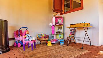 A playroom with a doll in a pink stroller, a toy car, and a toy kitchen set.