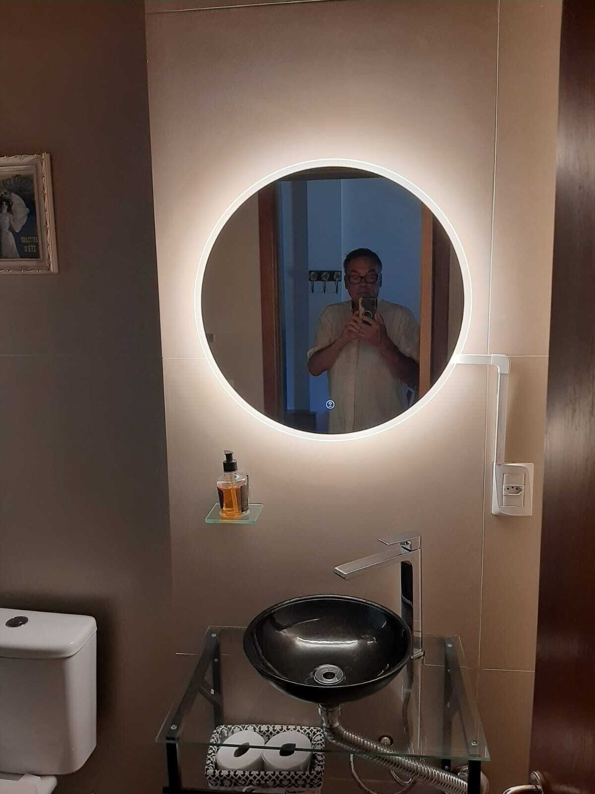 Ein Badezimmer mit rundem Spiegel, Waschbecken und Toilette.