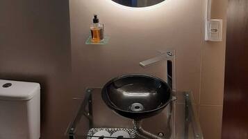 Ein Badezimmer mit rundem Spiegel, Waschbecken und Toilette.