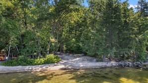 A clear river with a sandy bank and dense trees in the background. - SHORT WALK TO A LARGE SANDY BEACH (FRYE ISLAND)