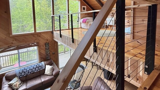 A wooden cabin with a loft bedroom, large windows, and a staircase. - SHORT WALK TO A LARGE SANDY BEACH (FRYE ISLAND)