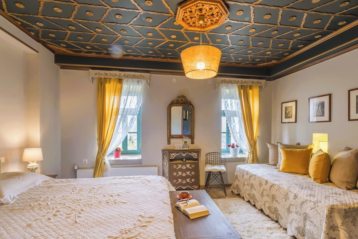 Een hotelkamer met een klassiek design, met twee bedden, een houten dressoir, een spiegel en een kroonluchter.