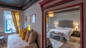 Een slaapkamer met een groot bed, een nachtkastje, een stoel en een raam met gordijnen.